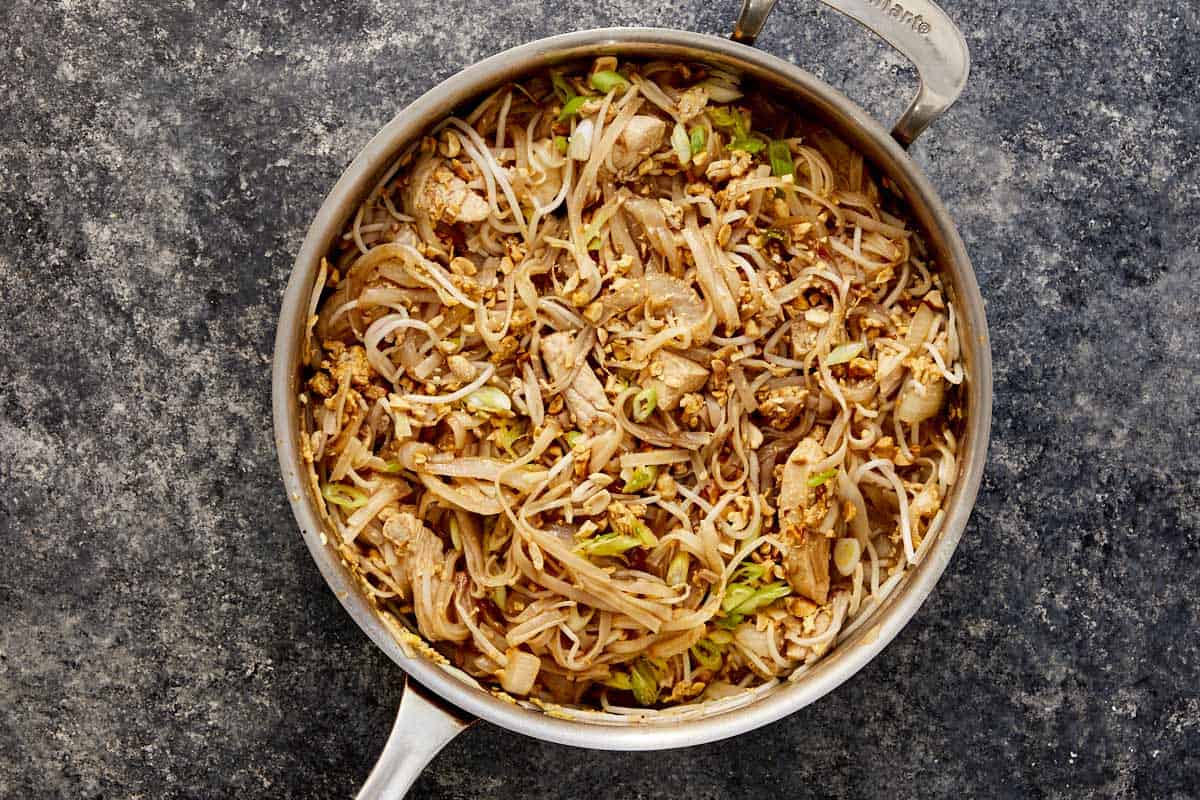 Pan of Pad Thai with chicken, tofu, eggs, bean sprouts, and peanuts mixed together.