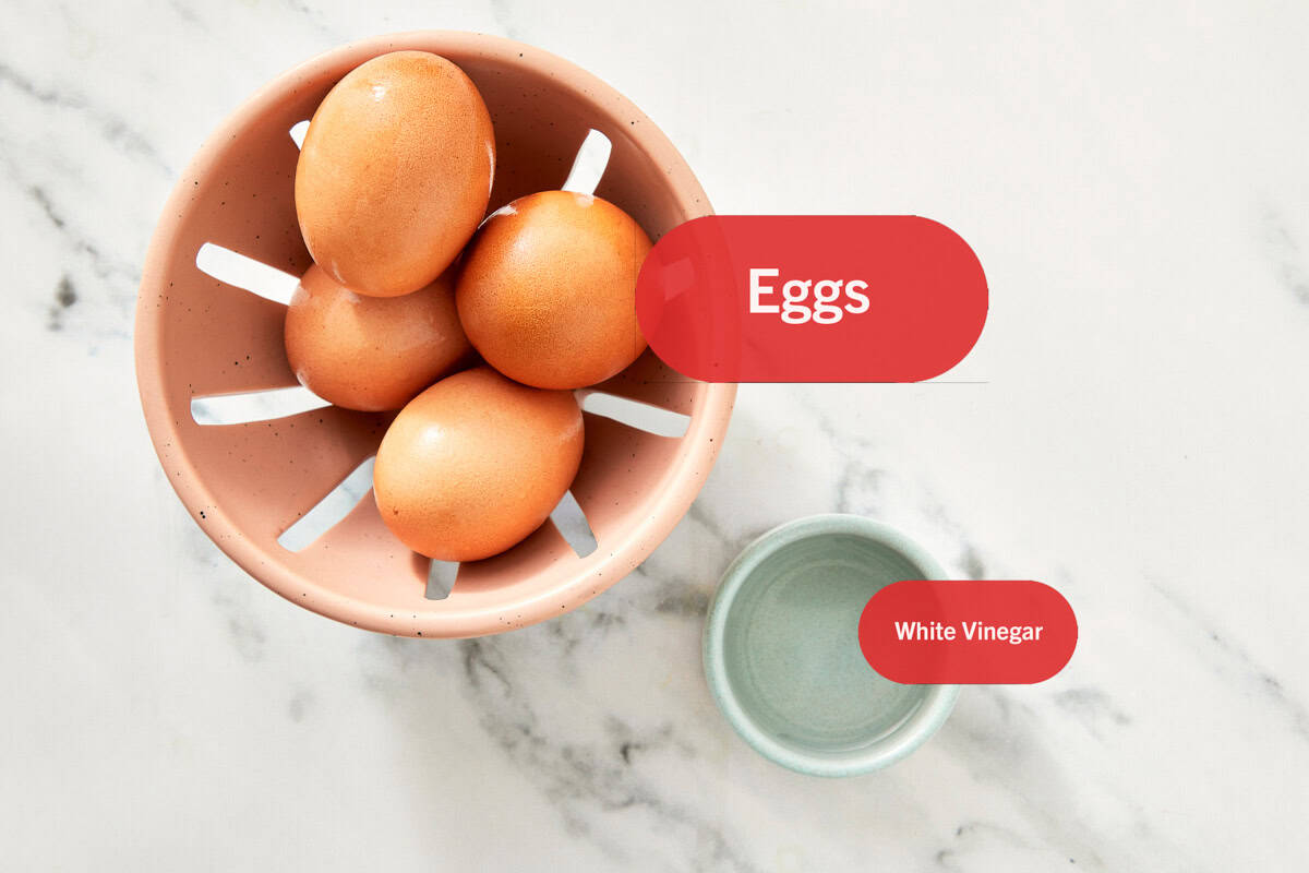 Top-down view of poached egg ingredients labeled: four raw eggs and white vinegar in small bowls on a marble surface.