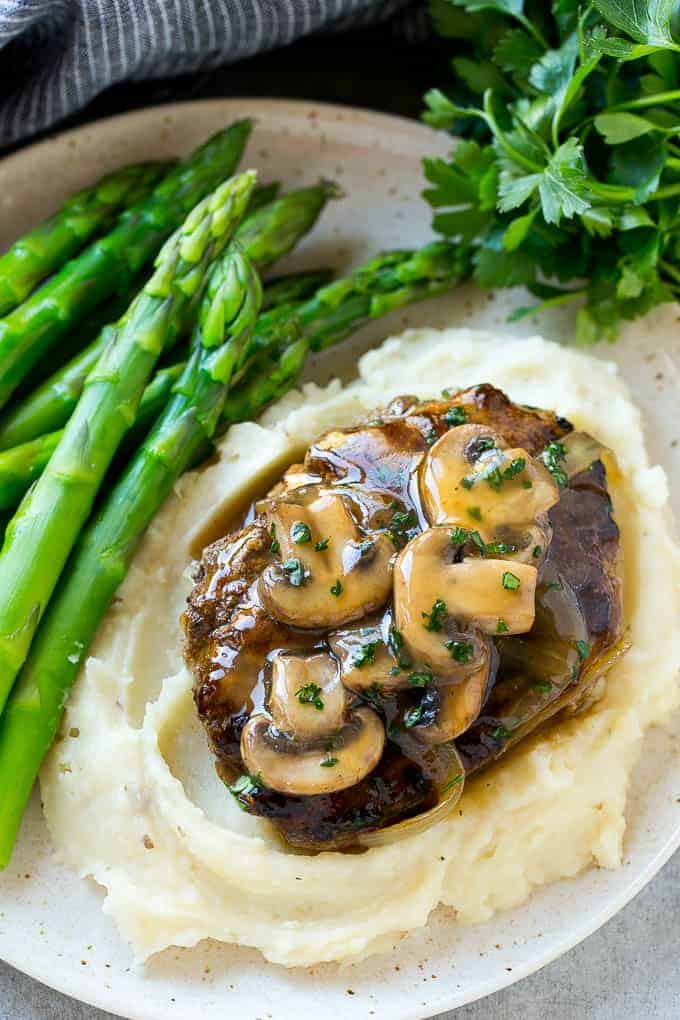 Salisbury steak is good served over mashed potatoes with a green vegetable on a fancy plate.