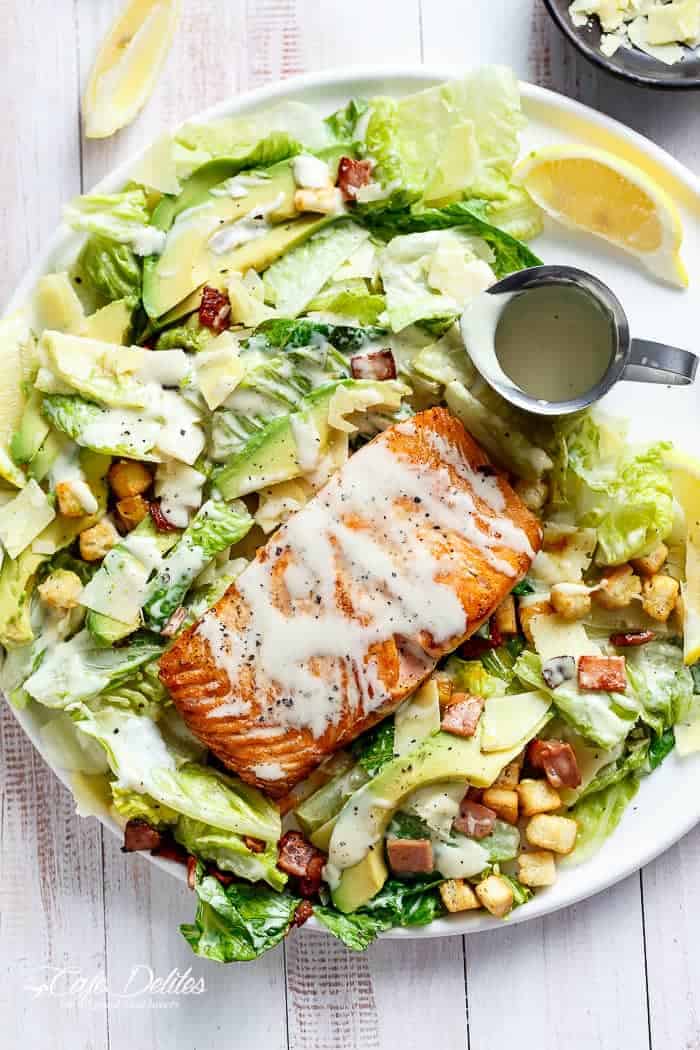 Crispy pan fried Salmon meets Caesar with creamy avocado slices, crunchy croutons, the tang of shaved parmesan cheese, a good runny poached egg on top and a lightened up Caesar dressing!