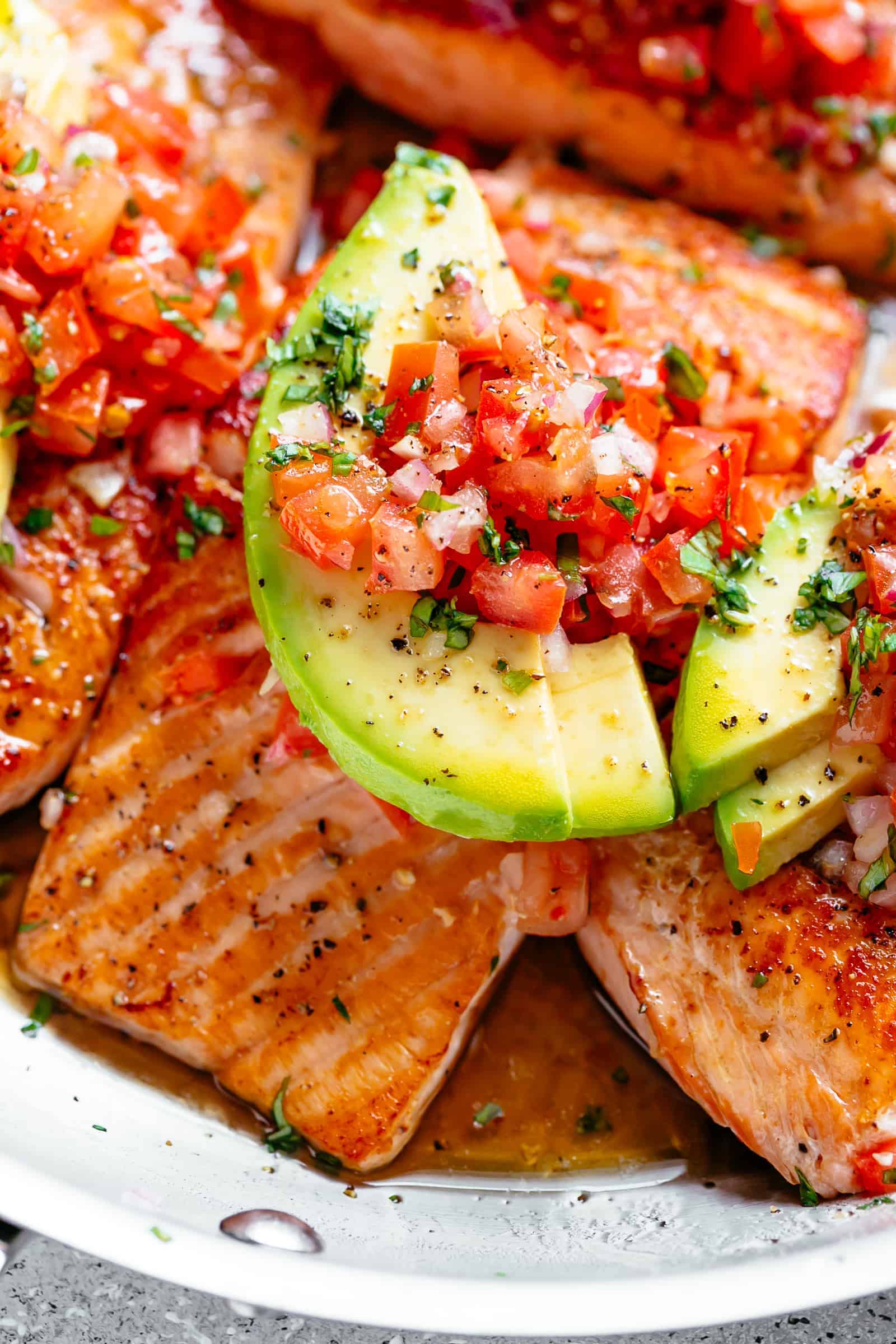 Pan Seared Salmon in a buttery garlic lemon sauce, topped with a fresh tomato salsa and avocado slices!