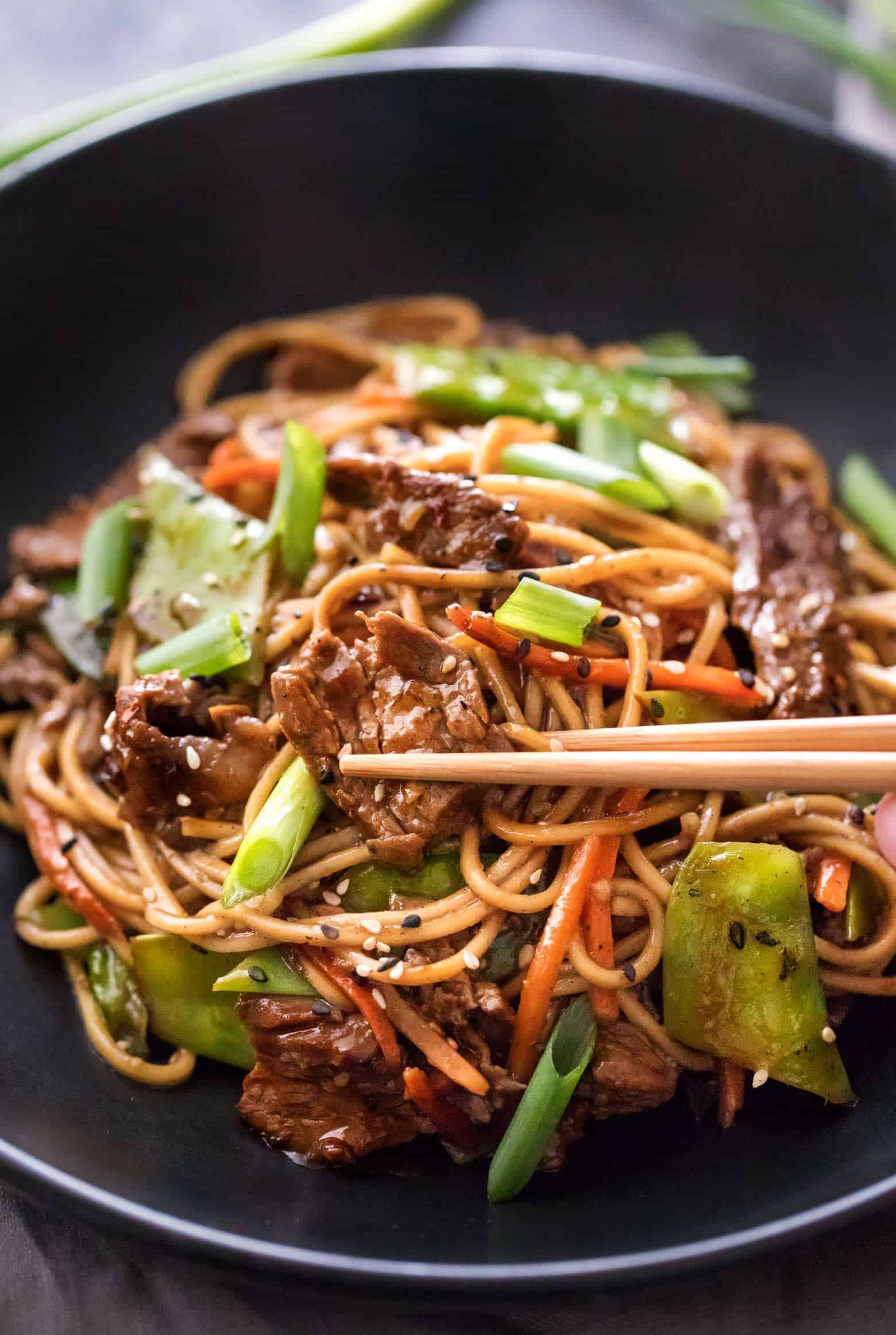 Beef stir fry noodles in bowl with chopsticks
