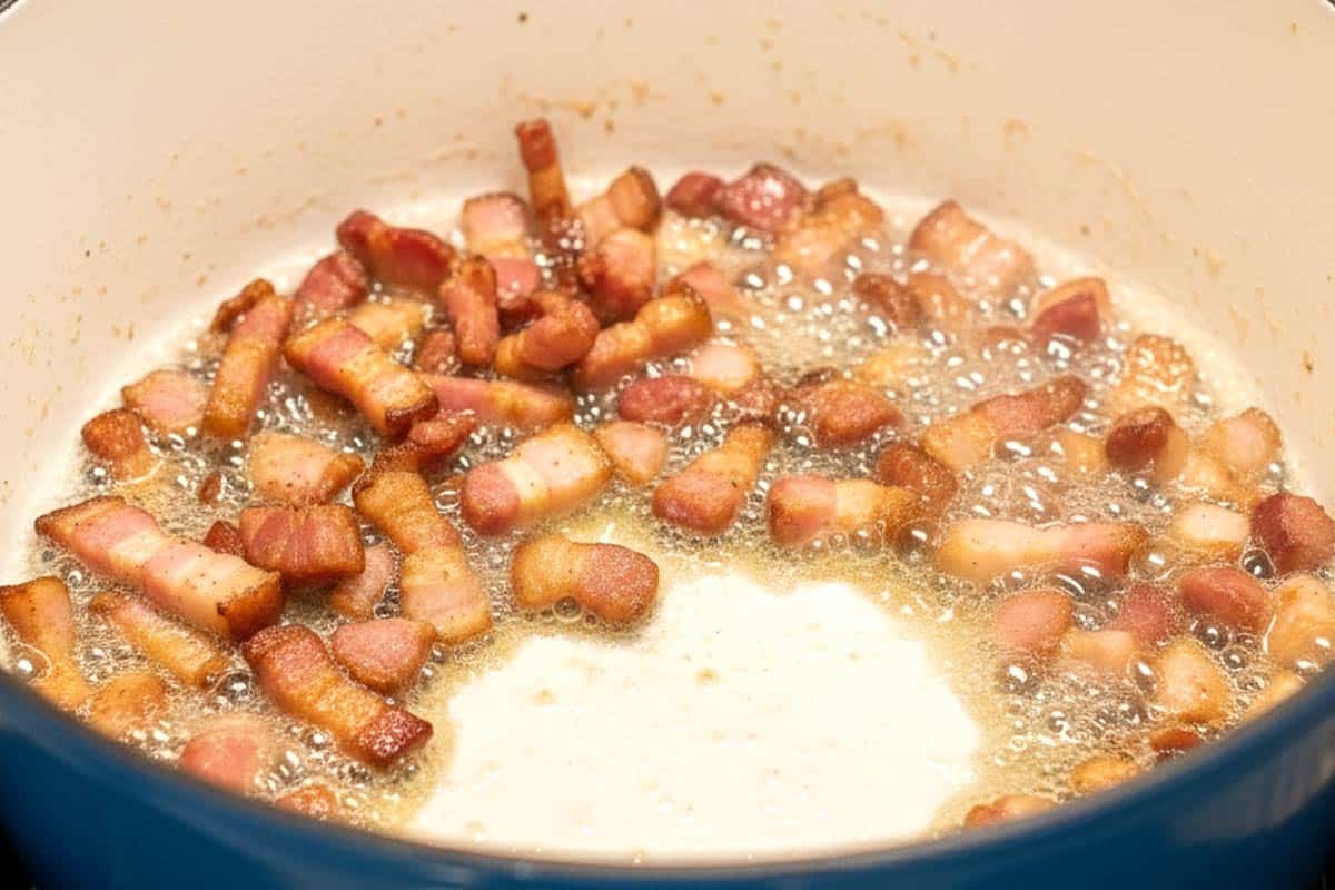 Frying the chopped bacon in a large pot.