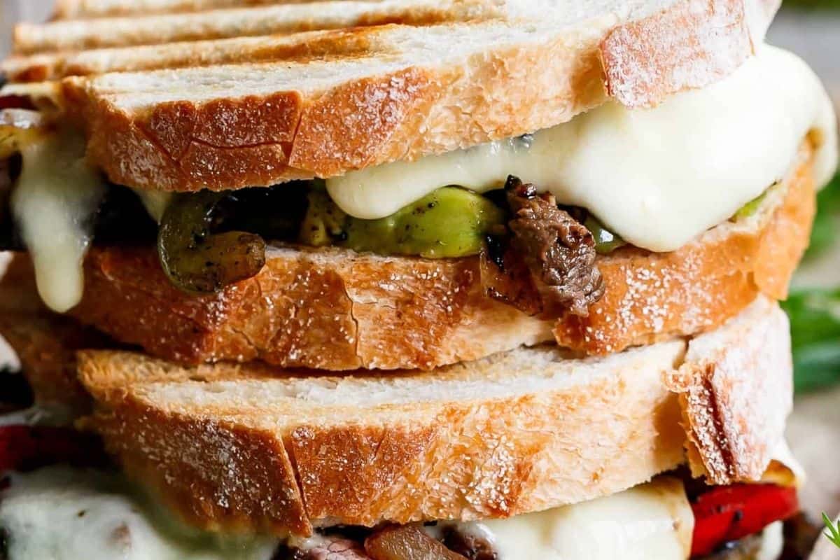 Layer the bread with peppers, onions, sliced steak, yoghurt or sour cream, avocado and mozzarella