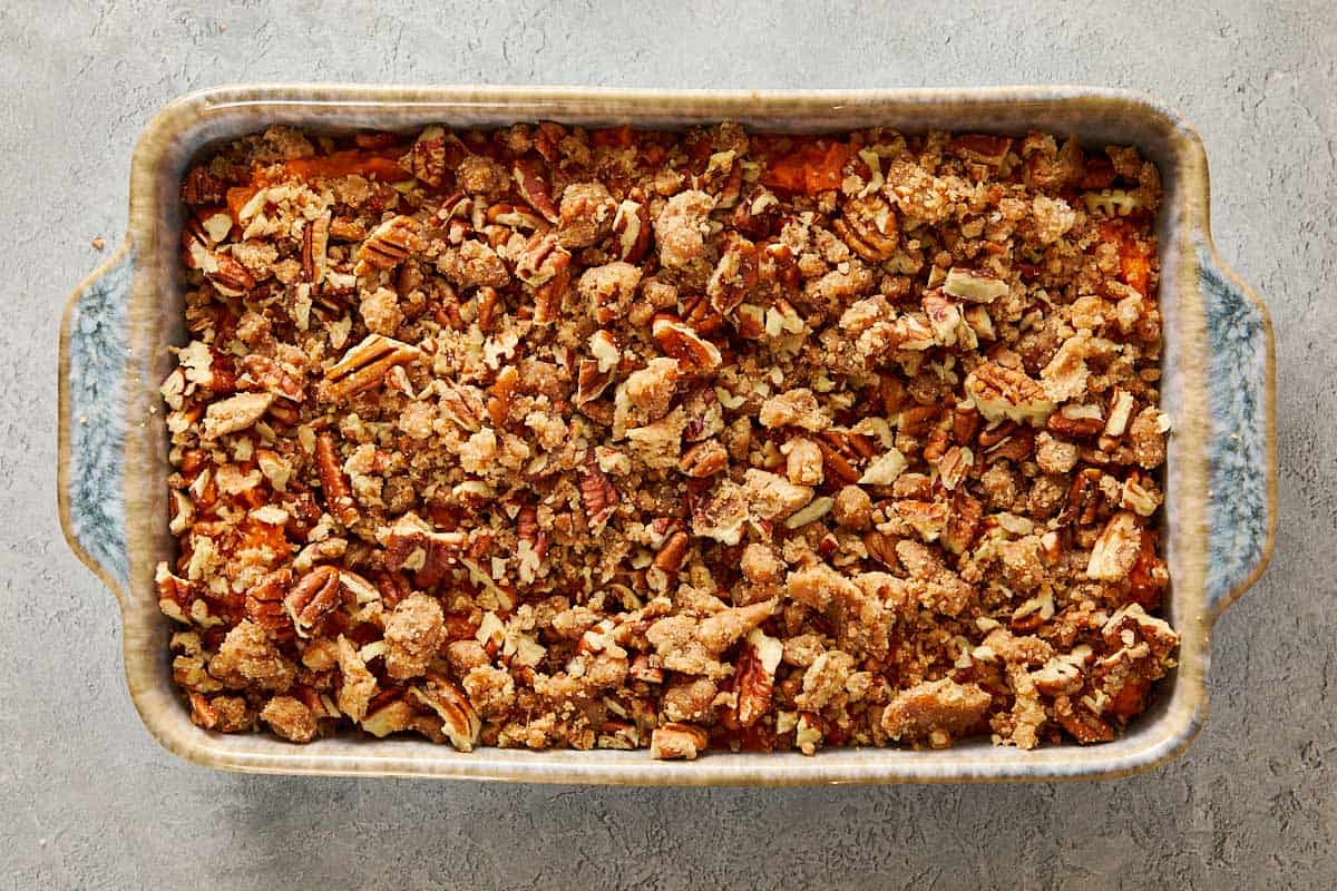 Unbaked sweet potato casserole topped with large white marshmallows spread over a pecan streusel layer