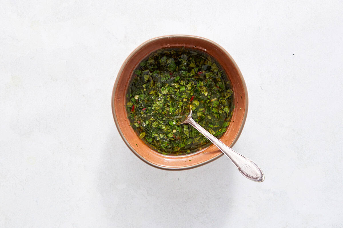 Bowl of herb-lime Thai dressing with a spoon.