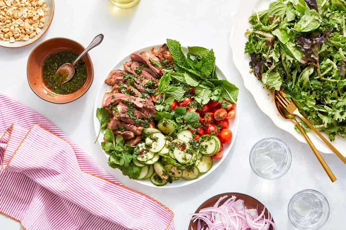Sliced steak and vegetables drizzled with dressing, ready to assemble.