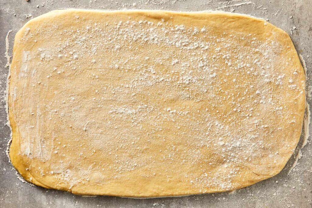 Dough rolled into a large rectangle on a floured surface