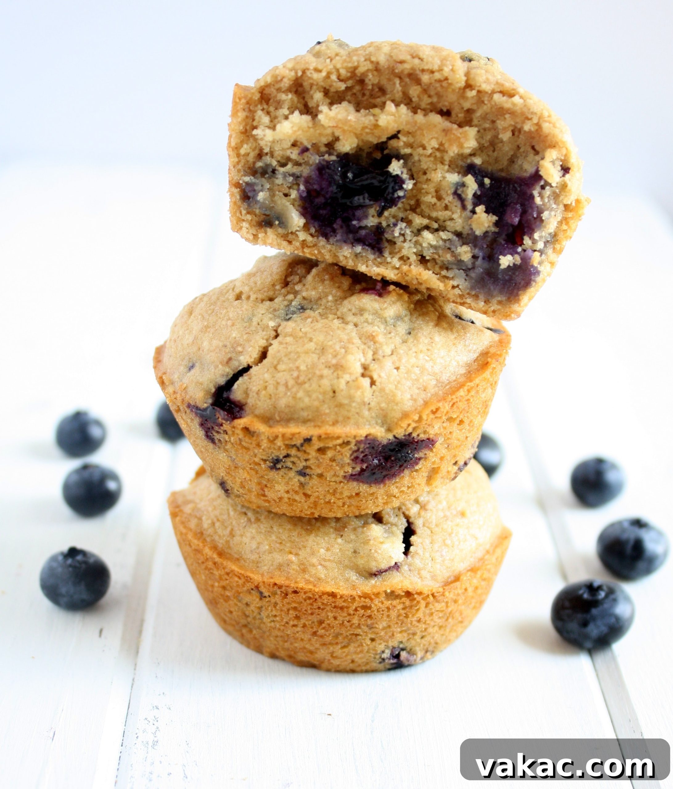 Wholesome Blueberry Morning Muffins 3 A stack of three whole wheat blueberry muffins. The top muffin has a bite missing.
