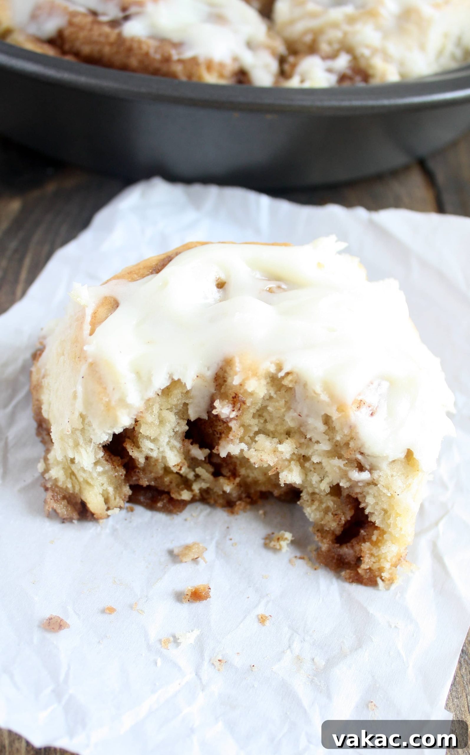 Cinnamon Rolls in a Snap 5 A 1 hour cinnamon roll with a bite missing on a piece of paper. A pan of cinnamon rolls rests in the background.