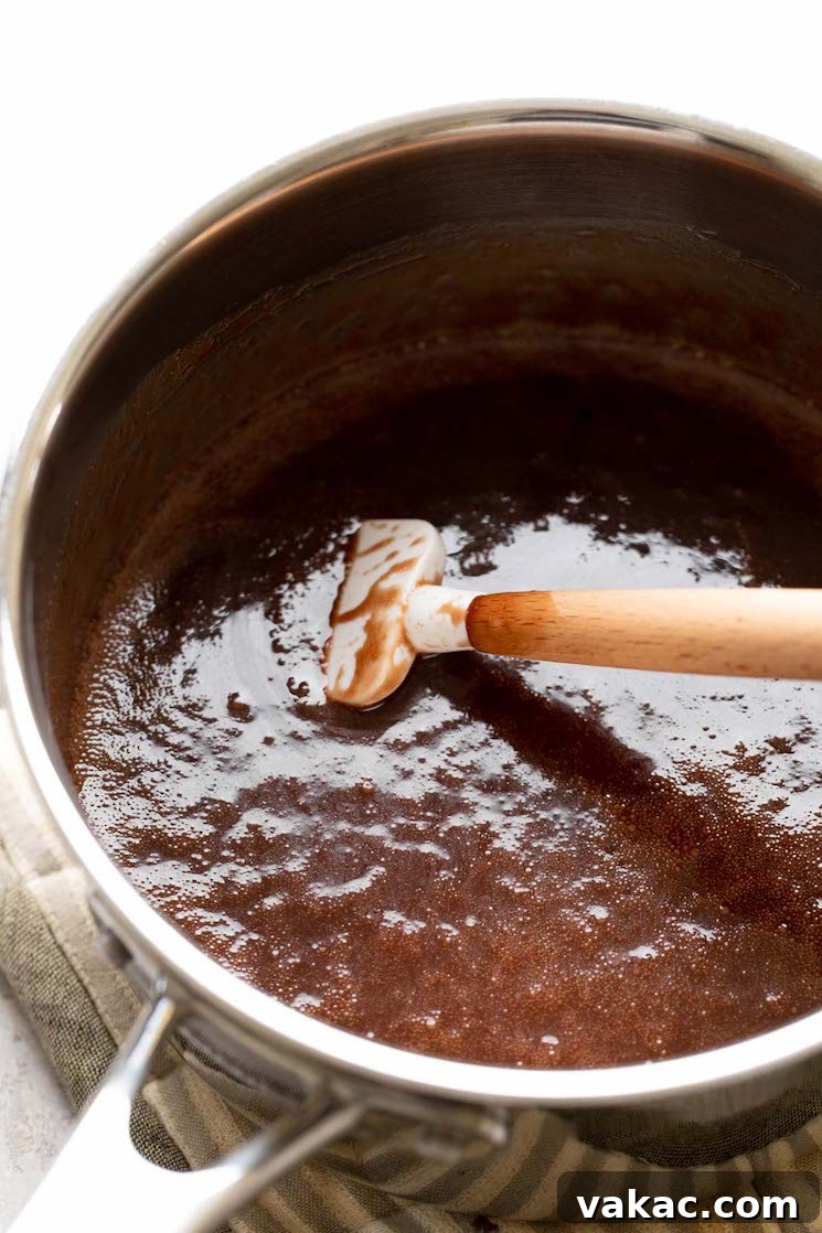 Stovetop Sweetness Made Simple 4 The initial no-bake cookie mixture—butter, sugar, milk, and cocoa powder—simmering gently in a large saucepan after melting and boiling for exactly one minute, with a rubber spatula resting inside.