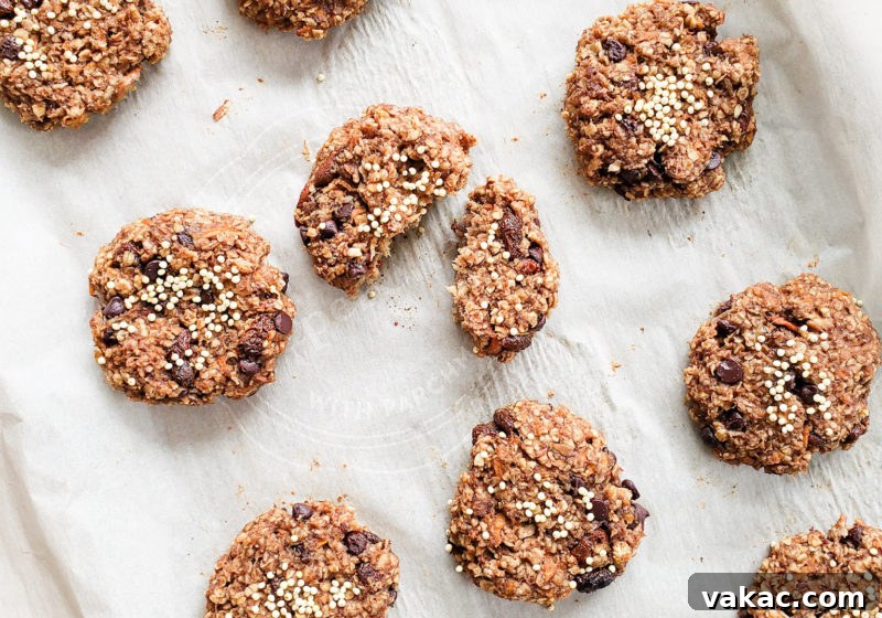 Make-Ahead Vegan Gluten-Free Carrot Cake Breakfast Cookies 3 A close-up view of freshly baked carrot cake breakfast cookies on a baking sheet, showcasing their wholesome texture and inviting golden-brown edges. Ingredients like oats, grated carrots, and specks of raisins are visible, emphasizing their natural appeal.