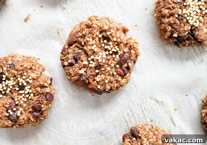 Make-Ahead Vegan Gluten-Free Carrot Cake Breakfast Cookies 4 A freshly baked batch of carrot cake breakfast cookies cooling on a parchment-lined baking sheet. The rustic texture and wholesome appearance of the cookies, rich with oats, carrots, and raisins, invite a healthy start to the day.