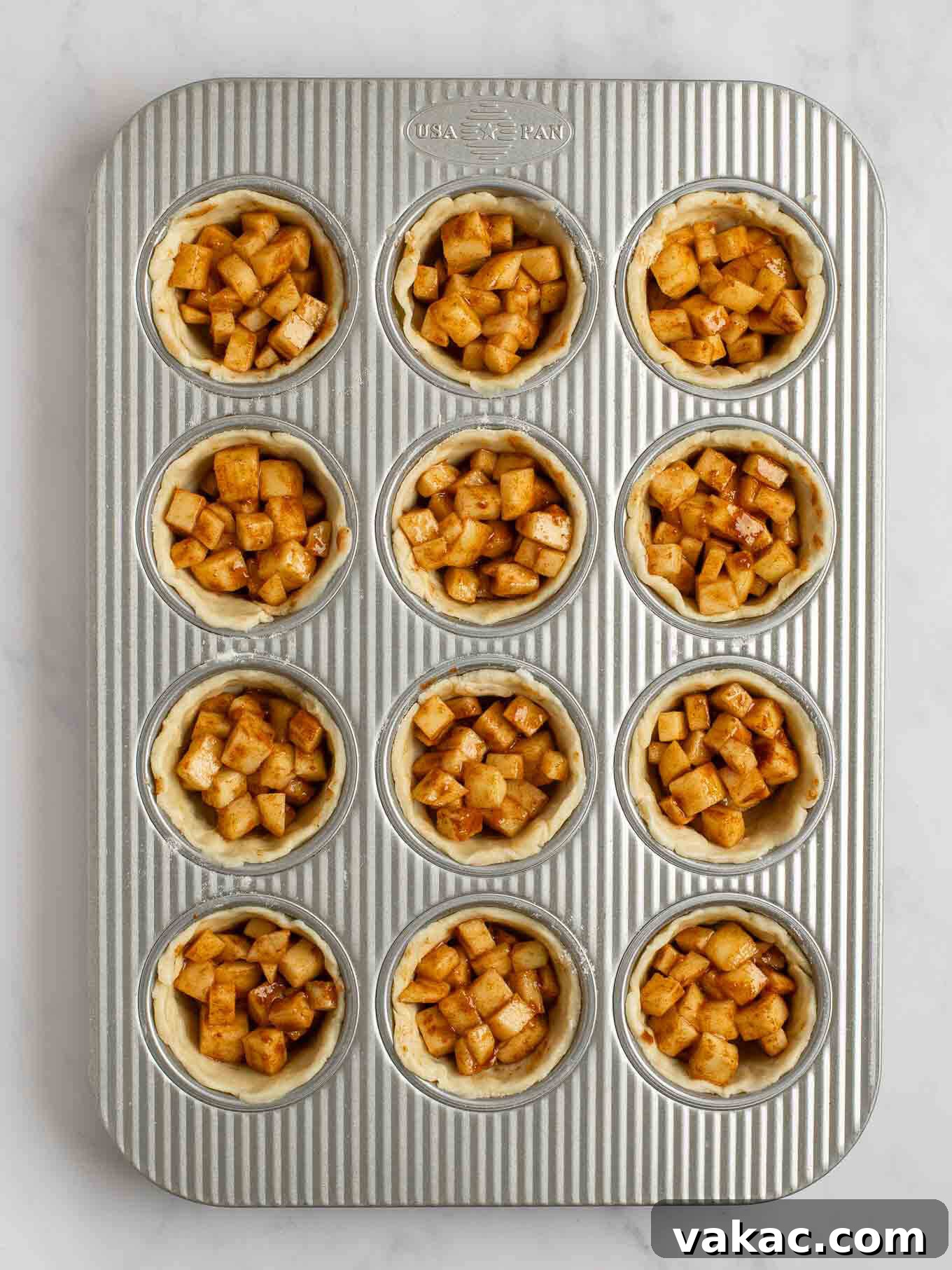 Sweet Apple Pie Bites 7 An overhead view of the apple pie filling evenly distributed between all of the pie crusts in a muffin pan.