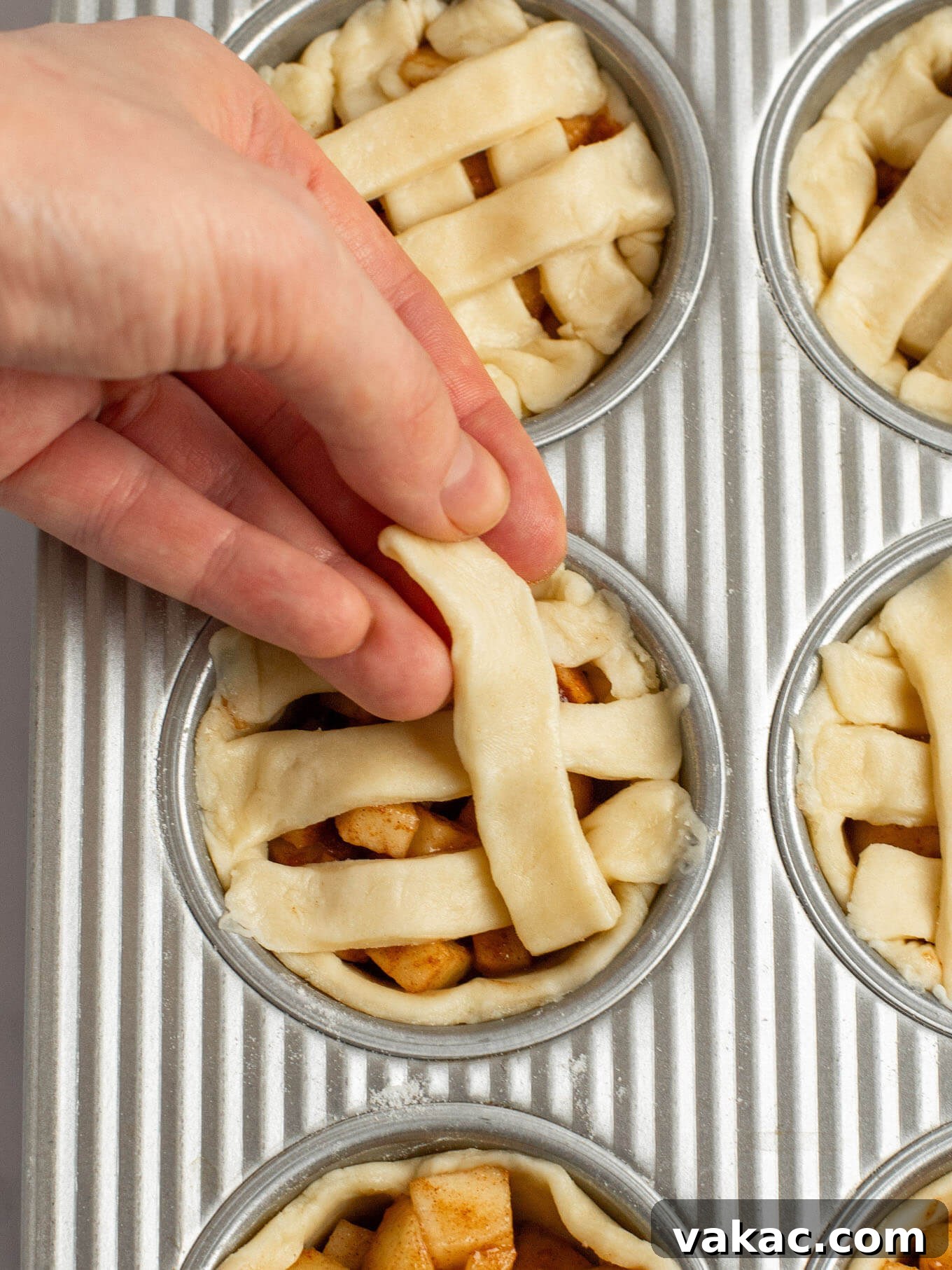 Sweet Apple Pie Bites 8 An angled view of small strips of pie crust being placed on top of the pies to create a lattice pie crust.