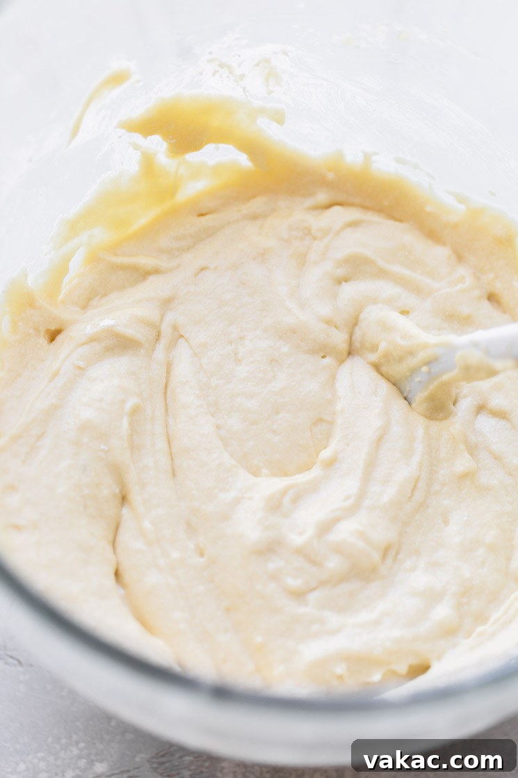 A glass mixing bowl holding cake batter that has been mixed up.