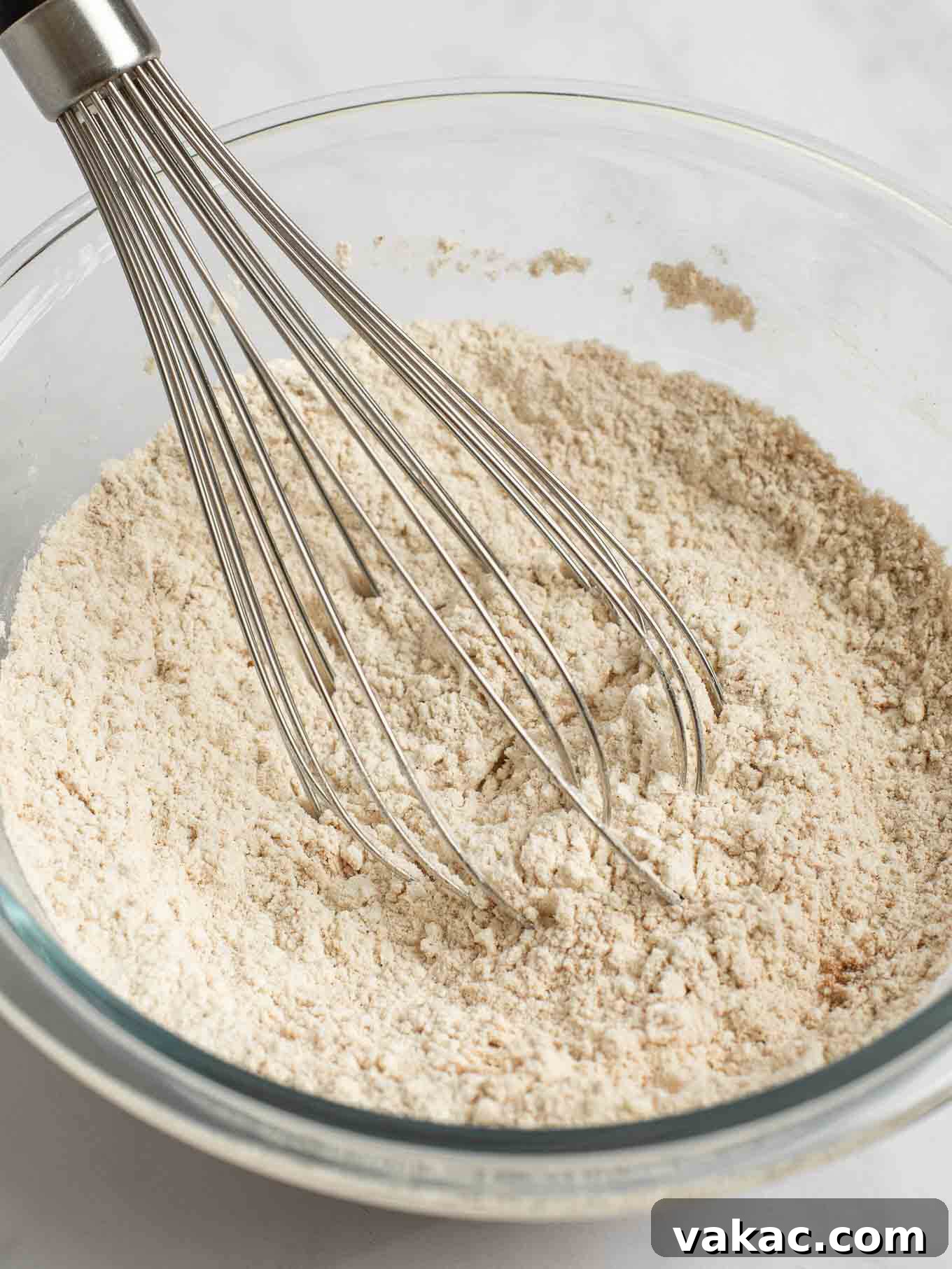 Spiced Pumpkin Snickerdoodles 4 Flour, pumpkin pie spice, cinnamon, baking soda, cream of tartar, and salt are whisked together in a clear glass mixing bowl, forming the dry ingredients for the snickerdoodles.