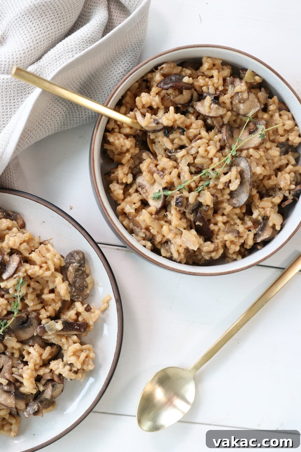 Creamy mushroom risotto in a white and brown bowl over a white food board. Ingredients include: mushrooms, garlic, parsley, arborio rice, white wine, vegetable stock, parmesan, butter