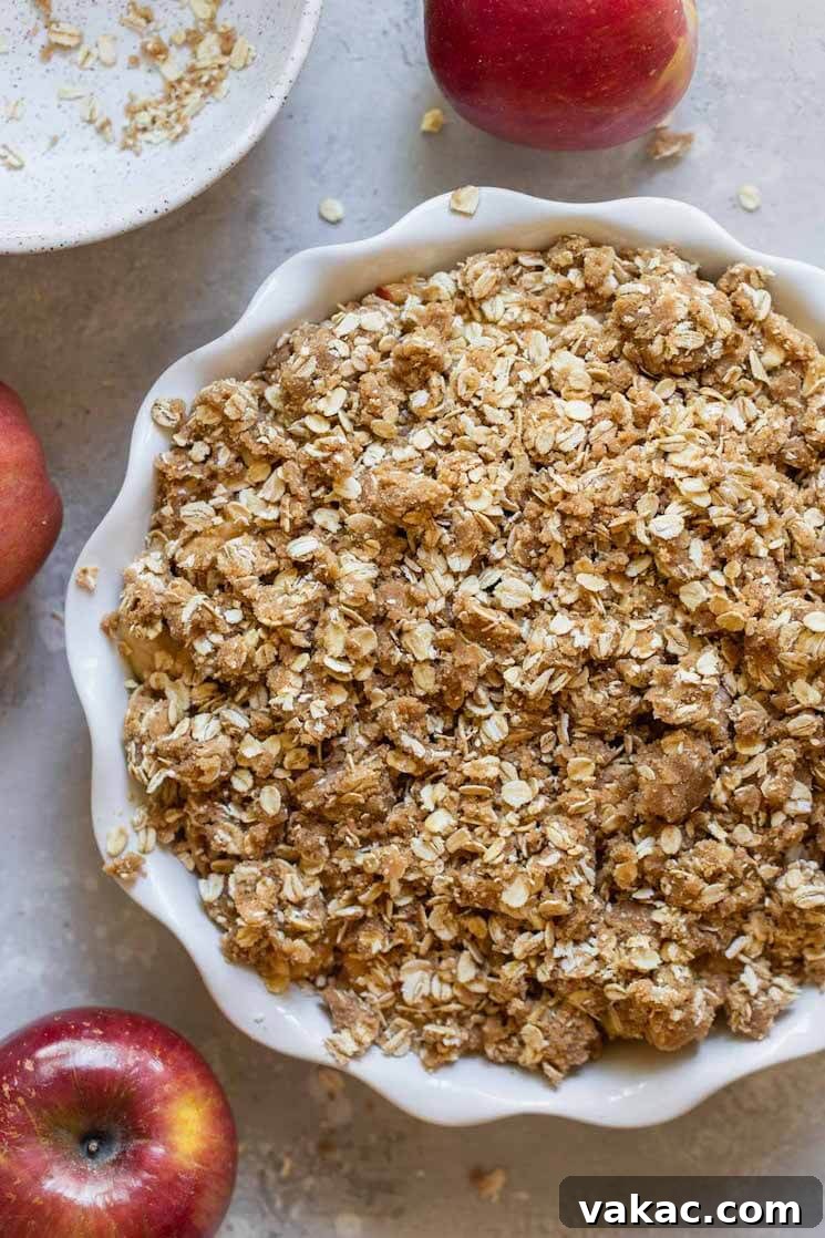 Simply Delicious Apple Crisp 4 An apple crisp ready to go in the oven surrounded by more apples.