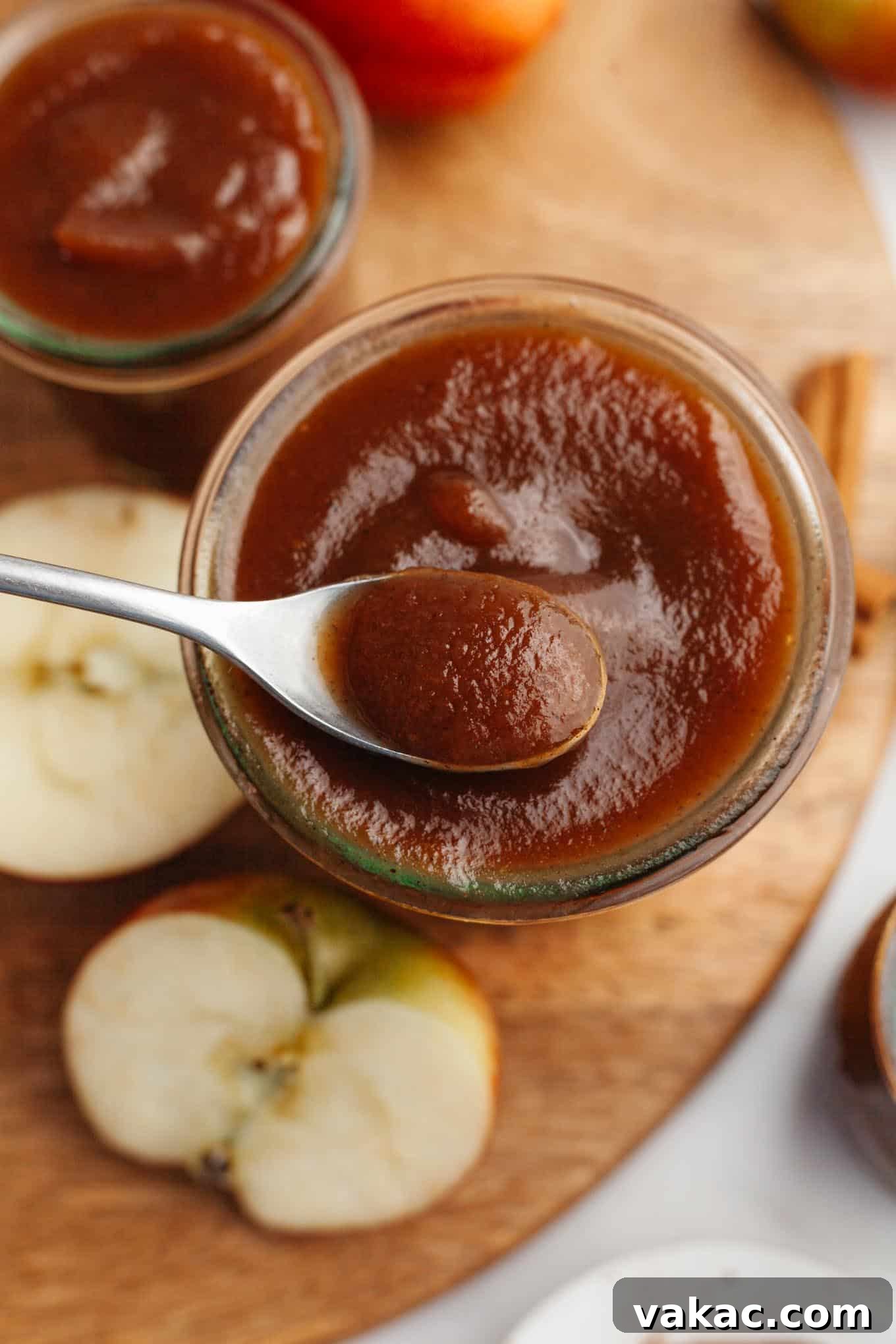 Classic Homemade Apple Butter Recipe 2 A beautifully smooth apple butter being spooned from a glass jar, highlighting its rich, dark amber color.