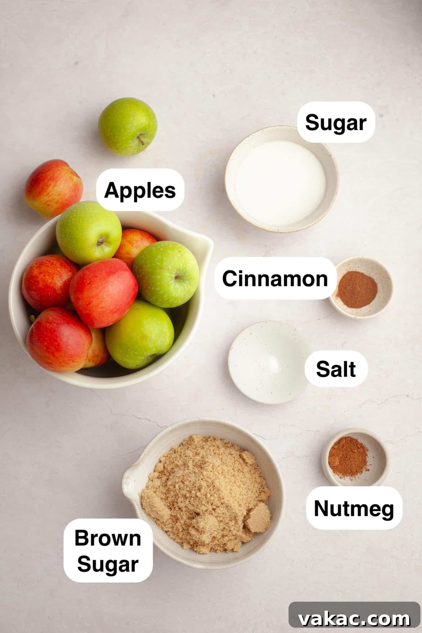Classic Homemade Apple Butter Recipe 3 An overhead shot showcasing the fresh ingredients required for homemade slow cooker apple butter: a variety of apples, brown sugar, granulated sugar, cinnamon, nutmeg, and a salt shaker.