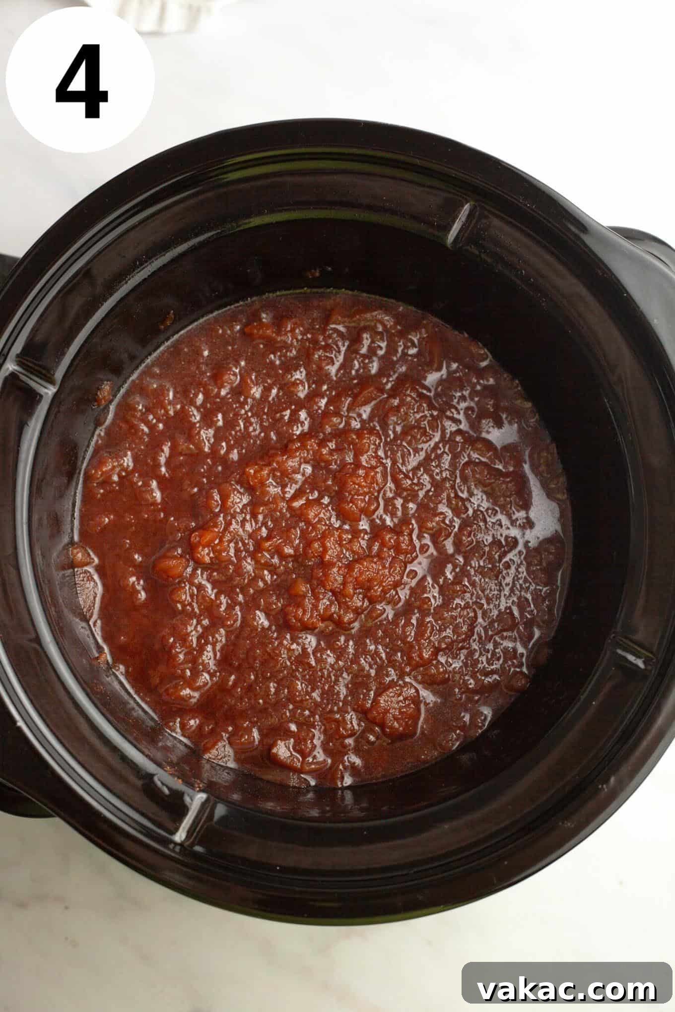Classic Homemade Apple Butter Recipe 7 A close-up, overhead shot of chunky apple butter within the slow cooker, having cooked down significantly but still retaining some texture.