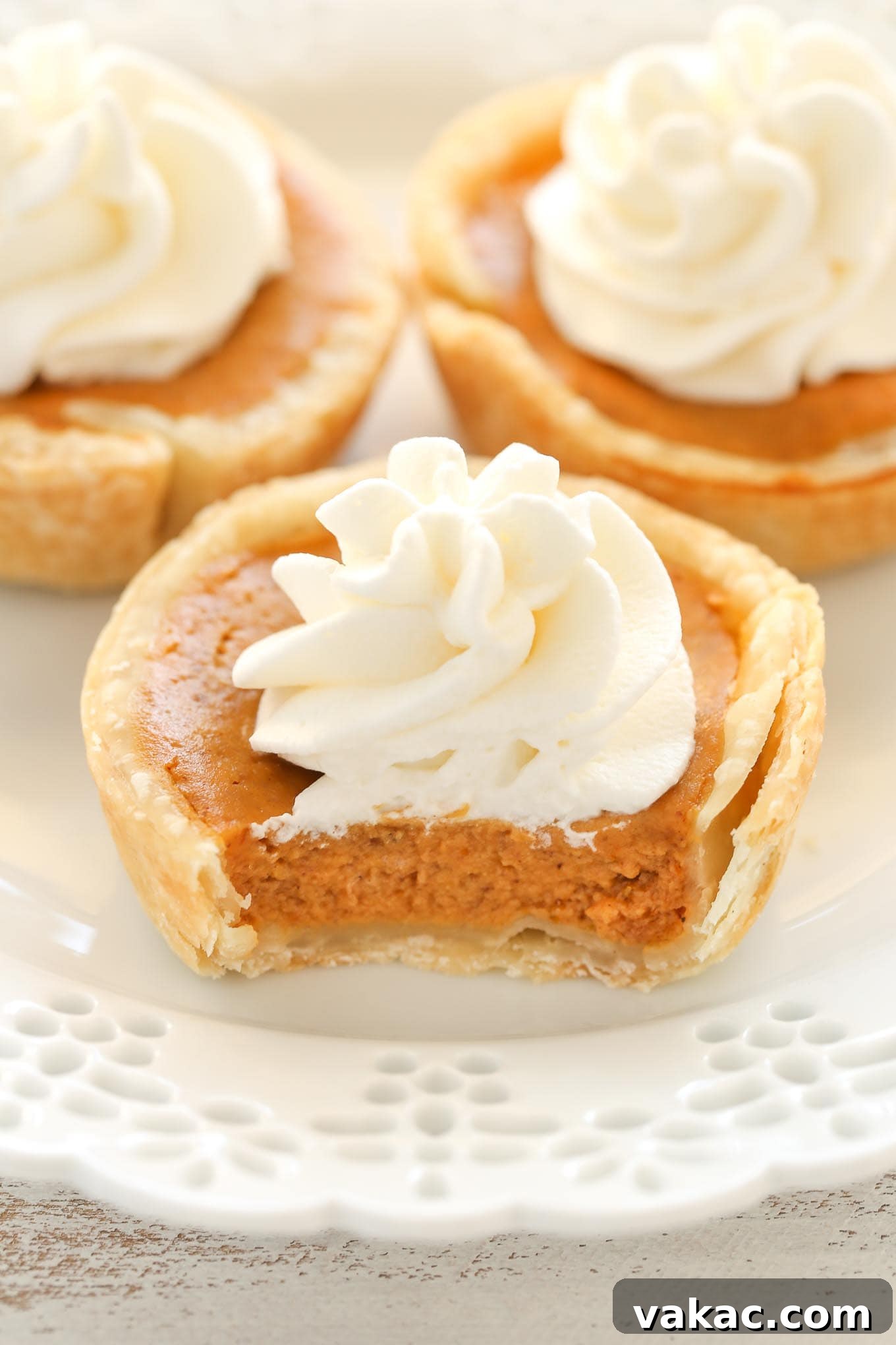 Pumpkin Pie Bites 11 Three mini pumpkin pies topped with whipped cream on a decorative white plate.