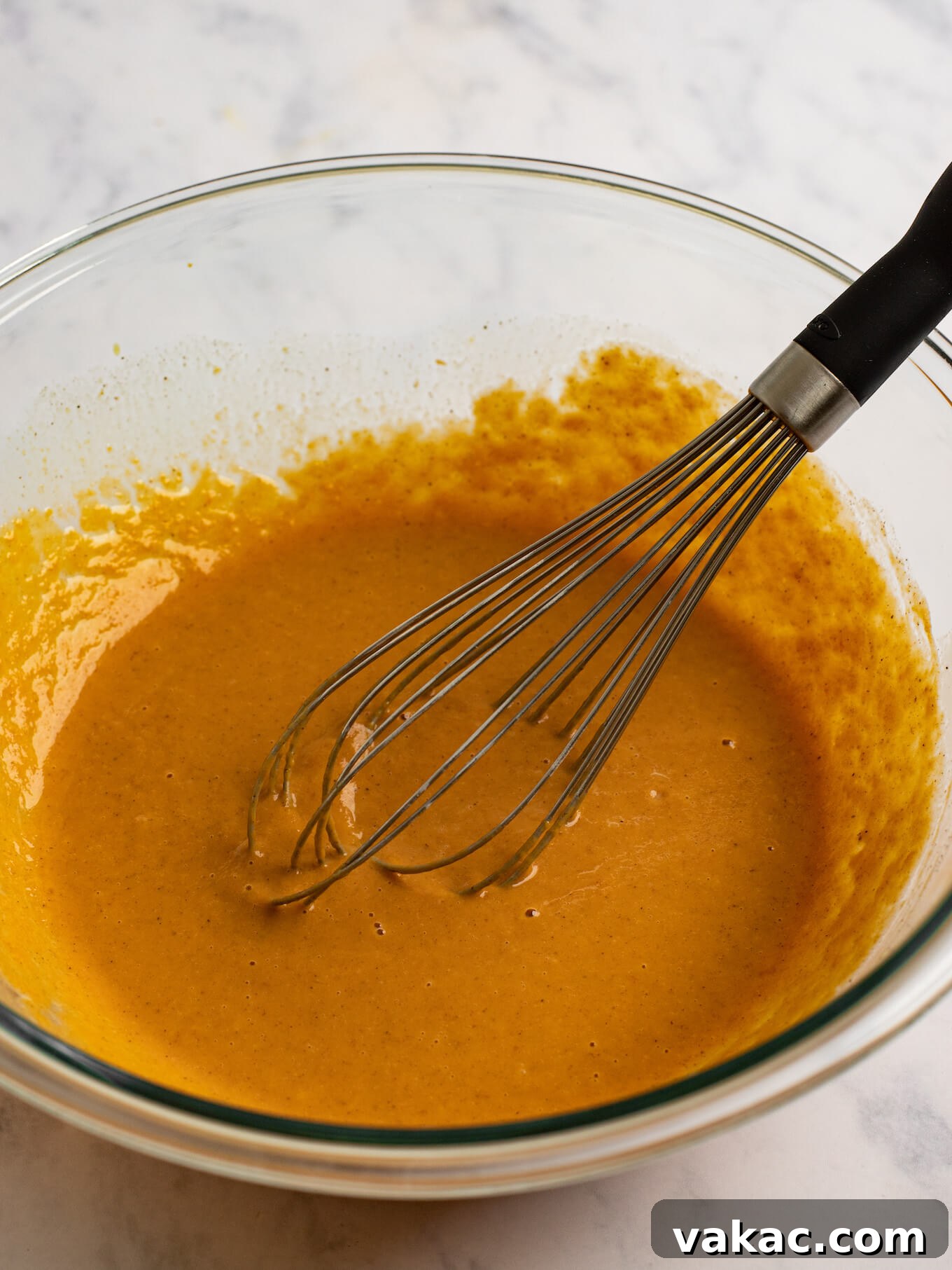 Pumpkin Pie Bites 7 The filling ingredients whisked together in a glass mixing bowl. A whisk rests on the side of the bowl.
