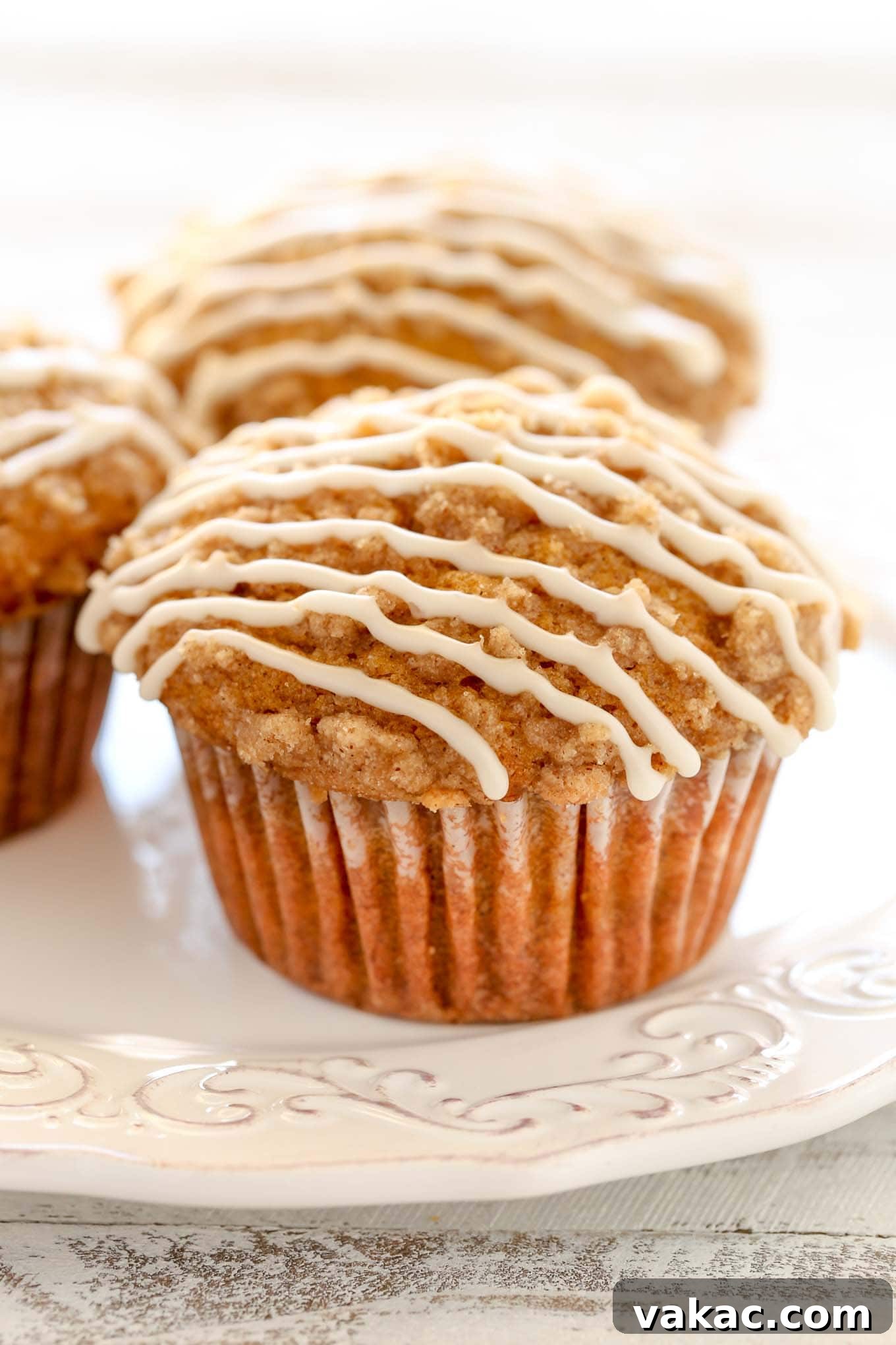 Three of the best ever pumpkin muffins topped with vanilla glaze on a white plate. 