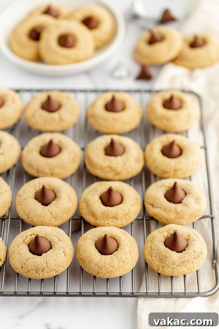A cooling rack holding peanut butter blossoms with more in the background on a plate and napkin.