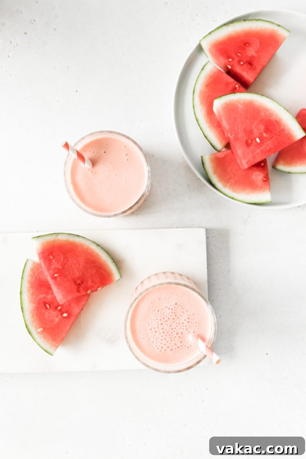 Refreshing 5-Minute Watermelon Banana Bliss 2 Two healthy watermelon banana smoothies in glass cups with striped pink and white straws, served on a neutral surface with fresh watermelon slices nearby. Key ingredients are visible: watermelon, banana, Greek yogurt, and lime.