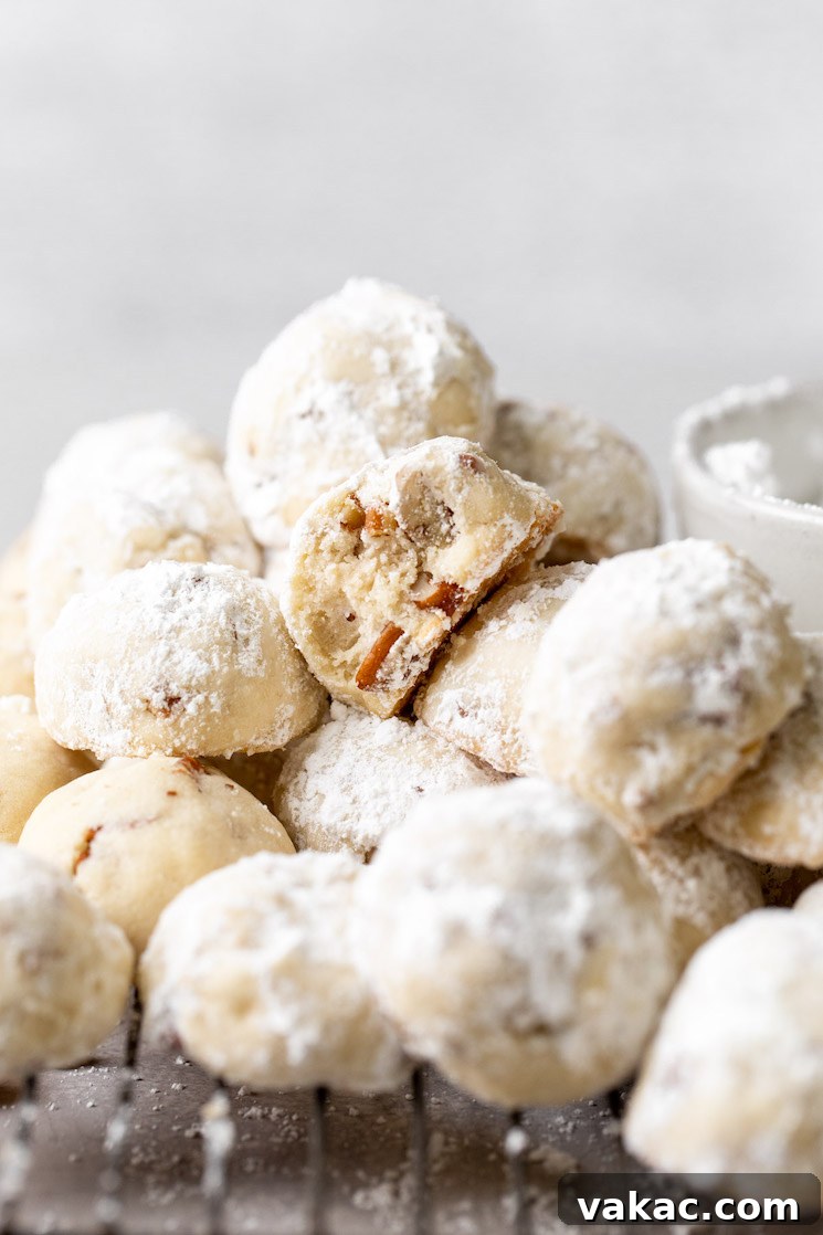 Powdered Perfection: Snowball Cookies 2 A pile of snowball cookies on a cooling rack with the one in the middle having a bite taken out of it.