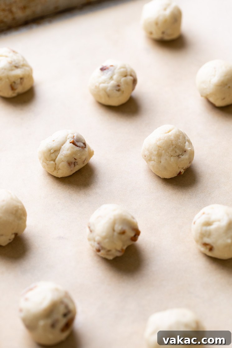 A baking sheet lined with parchment paper holding balls of cookie dough.