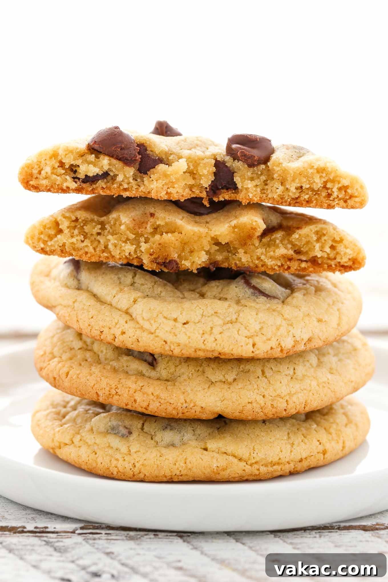 A stack of four chocolate chip cookies on a white plate.