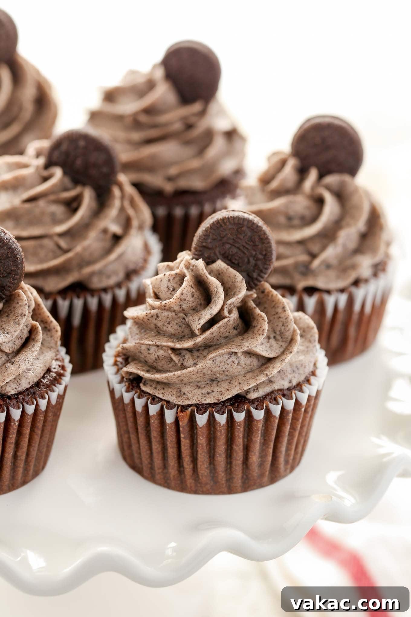 Oreo Overload Chocolate Cupcakes 2 Decadent Chocolate Oreo cupcakes arranged beautifully on a white cake stand, ready to be enjoyed.