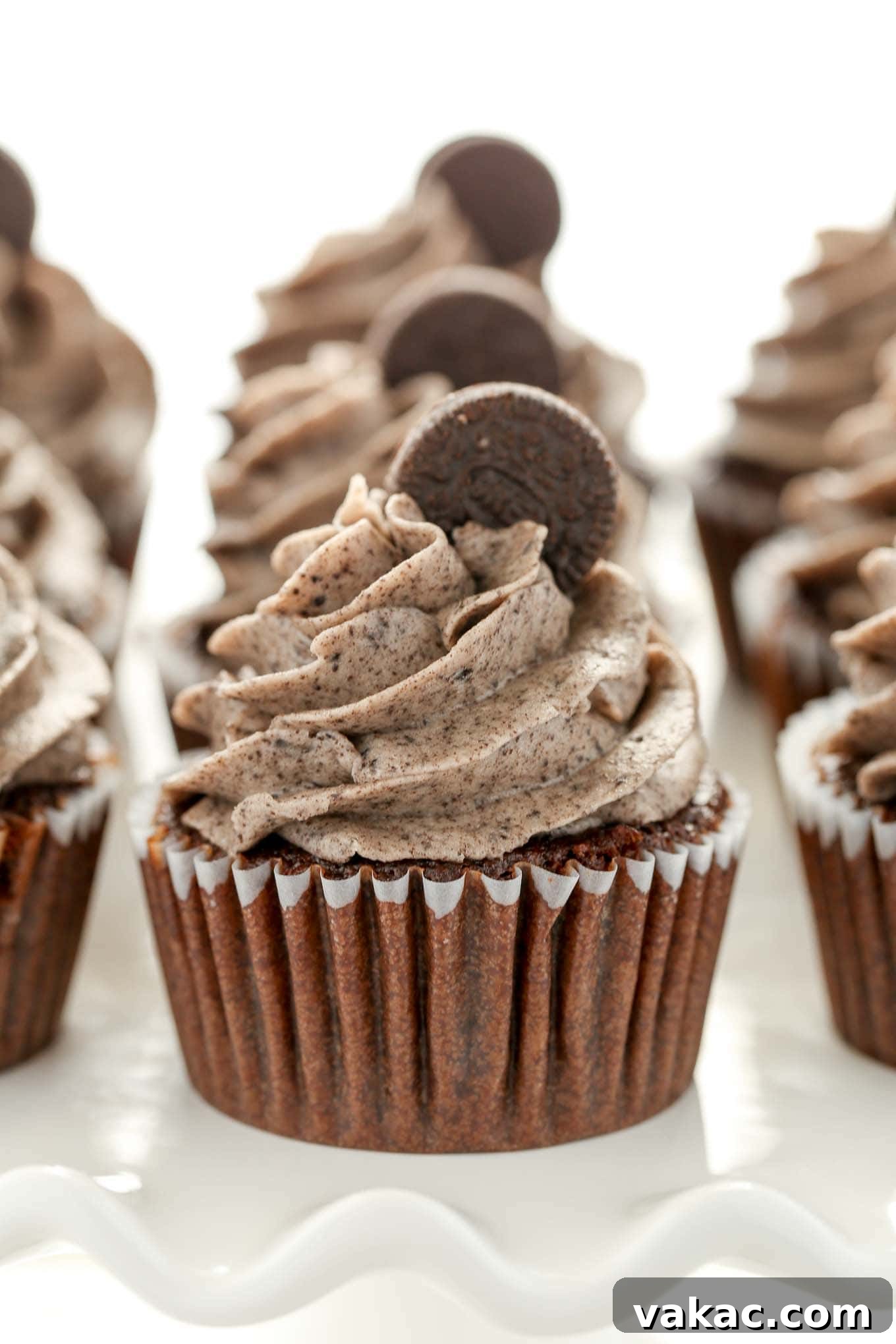 Oreo Overload Chocolate Cupcakes 5 A delectable display of three rows of Chocolate Oreo Cupcakes, beautifully arranged on a white cake stand.