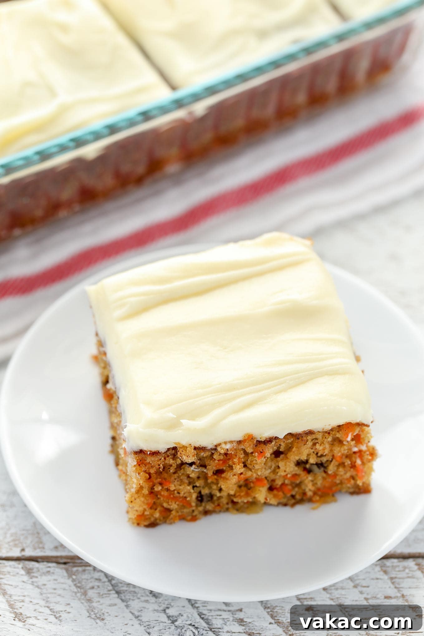 Tropical Carrot Bliss 4 A slice of pineapple carrot cake on a white plate. A pan of cake rests in the background.