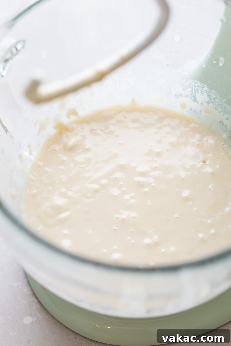 A glass mixing bowl holding the wet ingredients for the cinnamon roll dough before flour is added.