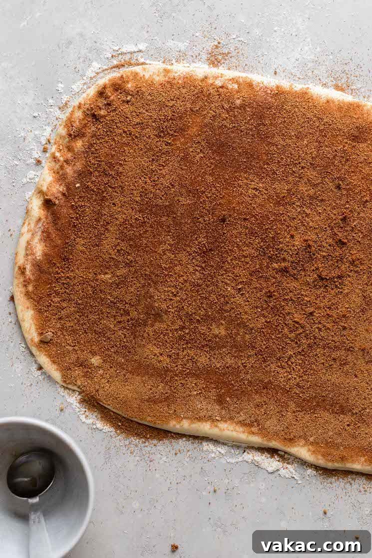 Cinnamon roll dough rolled out into a rectangle, covered with butter, brown sugar, and cinnamon.