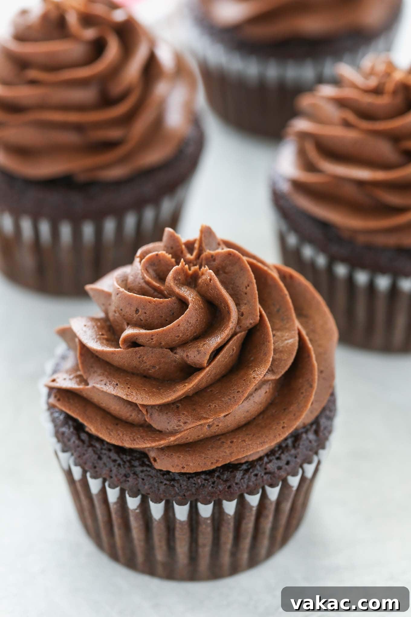 Velvet Chocolate Buttercream 4 Four beautifully piped chocolate cupcakes topped with generous swirls of homemade chocolate frosting, arranged appealingly.