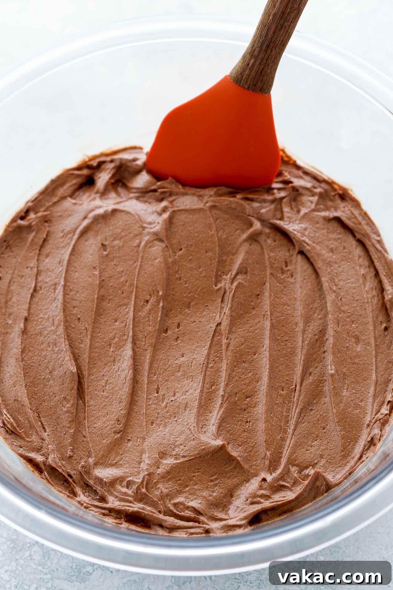 Velvet Chocolate Buttercream 5 A beautiful glass bowl full of rich, homemade chocolate buttercream frosting, with a clean spatula resting on the side, ready for spreading.