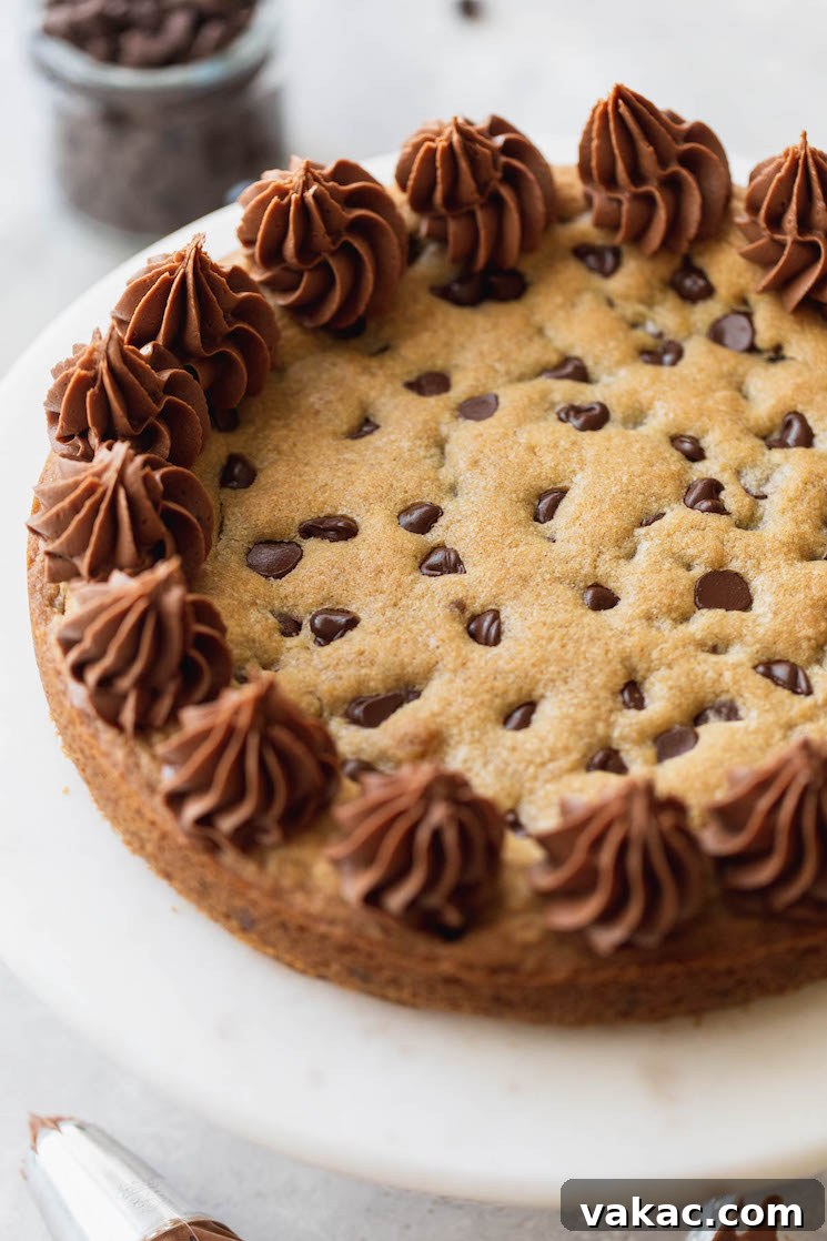 The Ultimate Chocolate Chip Cookie Cake 2 A finished cookie cake displayed on top of a marble cake stand, showcasing its chocolate chips and buttercream frosting.