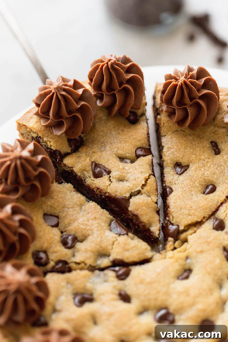 The Ultimate Chocolate Chip Cookie Cake 7 A chocolate chip cookie cake cut into slices, with one being removed with a cake server, revealing the soft interior.