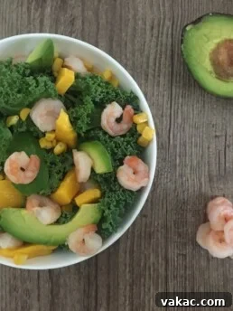 a bowl of prawn kale salad with avocado and corn