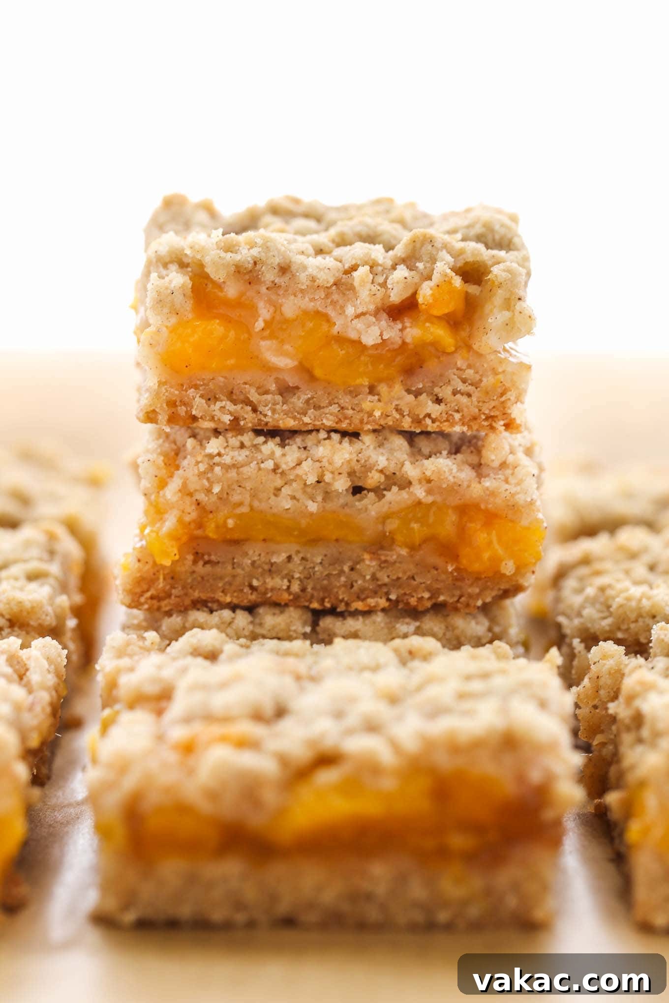 Sun-Kissed Peach Crumble Bars 2 A stack of golden-brown peach crumble bars, with additional bars artfully arranged around the main stack on a clean surface.