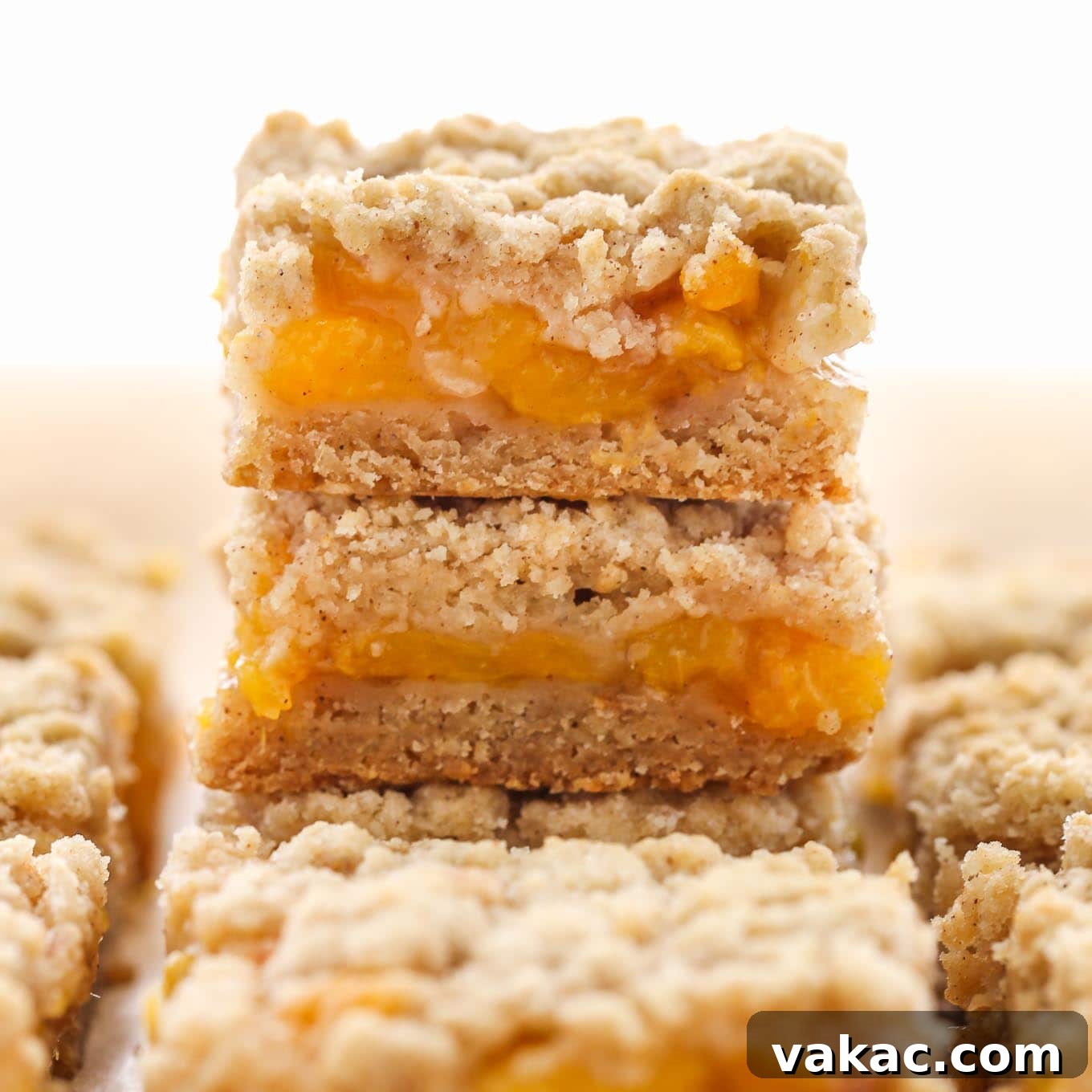 A stack of peach crumble bars, with additional bars surrounding the stack.