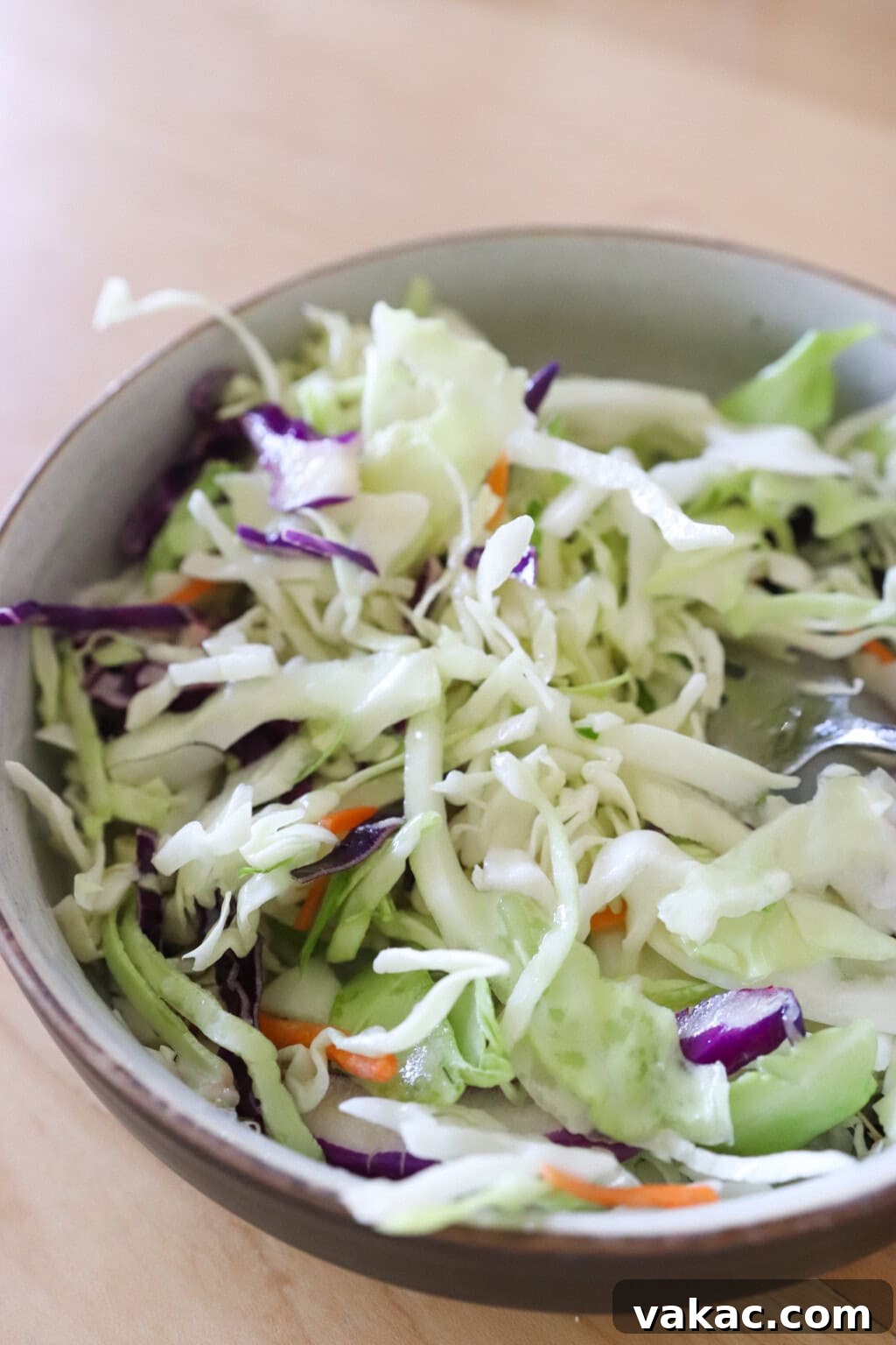 Sweet & Umami Maple-Soy Chicken Burger 6 Mixed cabbage slaw sits gets marinated in olive oil, lime juice, and salt in a white bowl on the counter