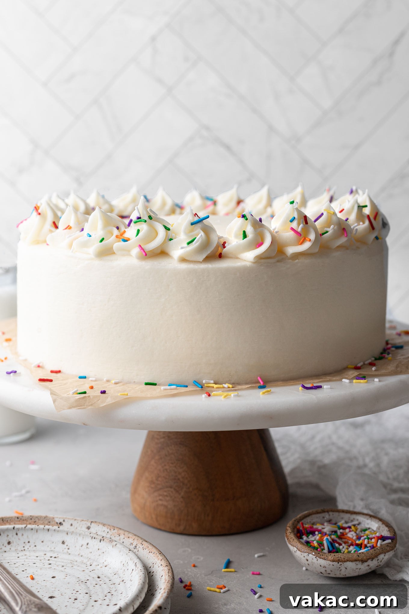 A beautifully frosted homemade white cake sitting gracefully on a cake stand, ready to be served.