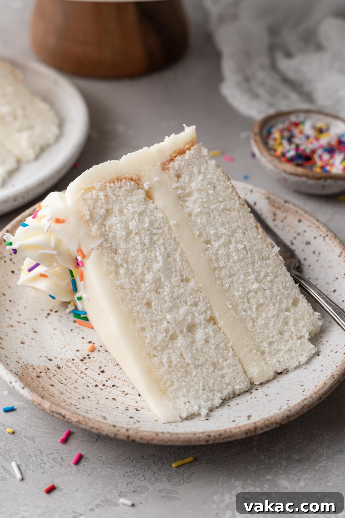 A perfectly portioned slice of homemade white cake on a clean dessert plate, invitingly ready to be eaten.
