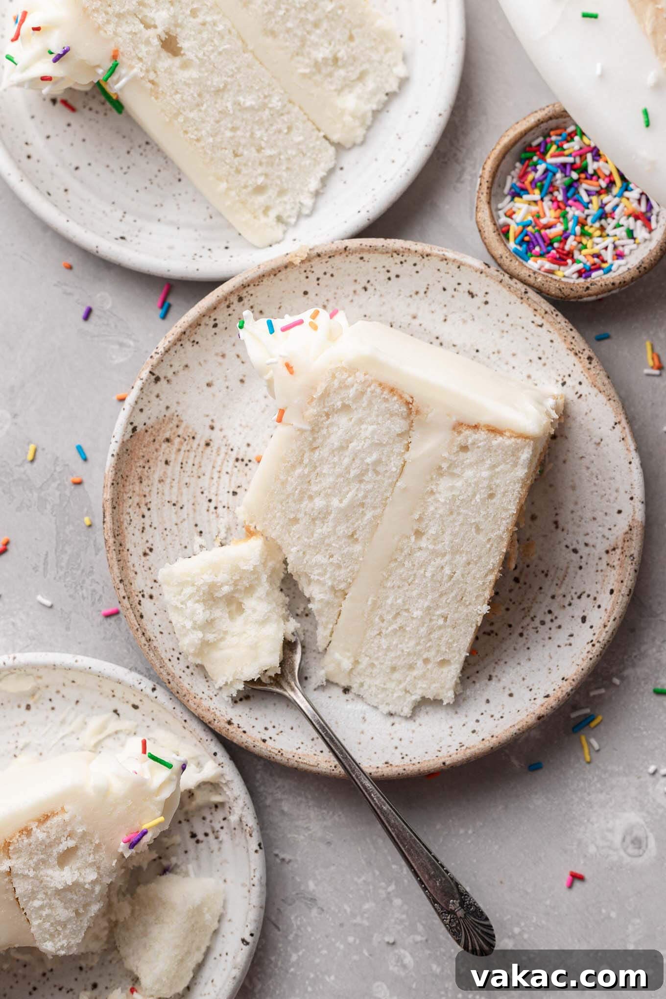 An overhead view of three slices of homemade white cake on individual dessert plates, each perfectly portioned and inviting.